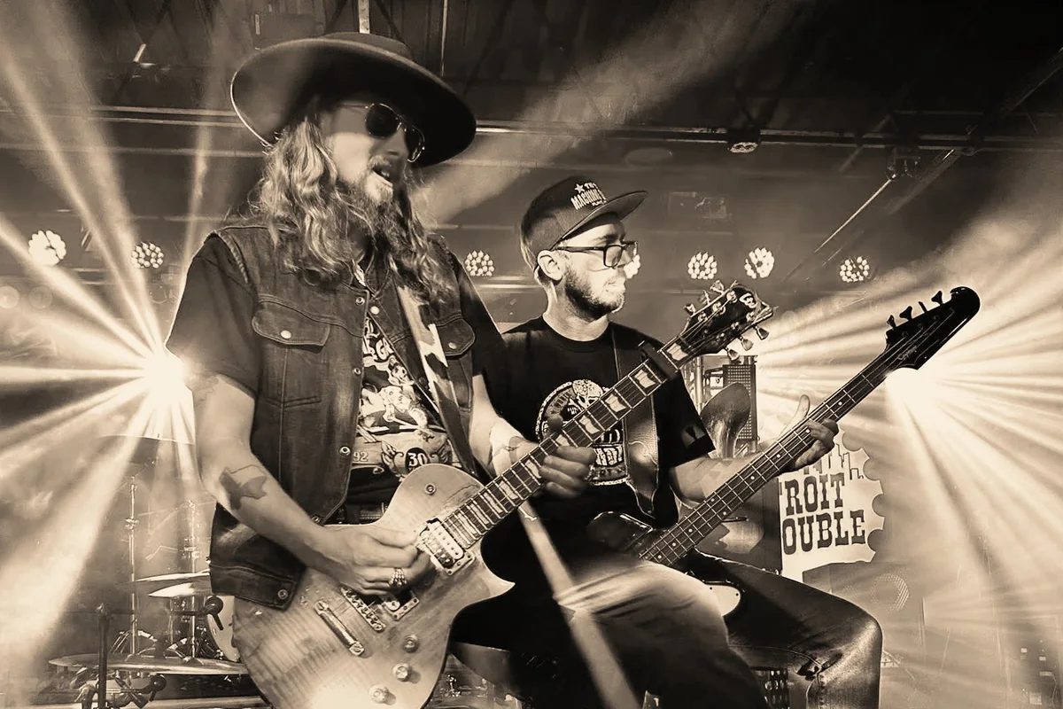 Kidd Lightning and Alex Blackburn playing together in stage lighting.