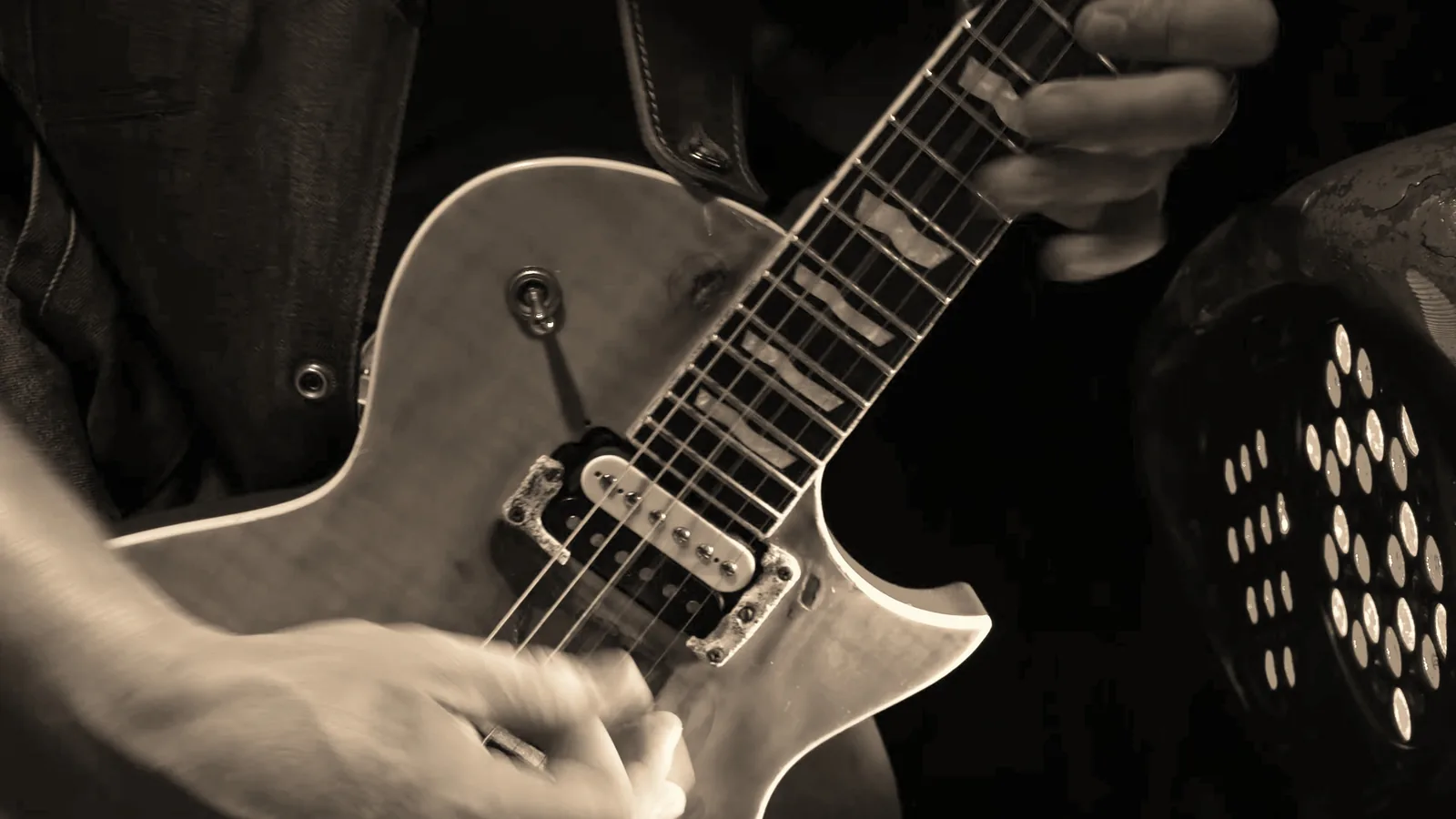 Close-up of Kidd Lightning’s hands on his guitar.