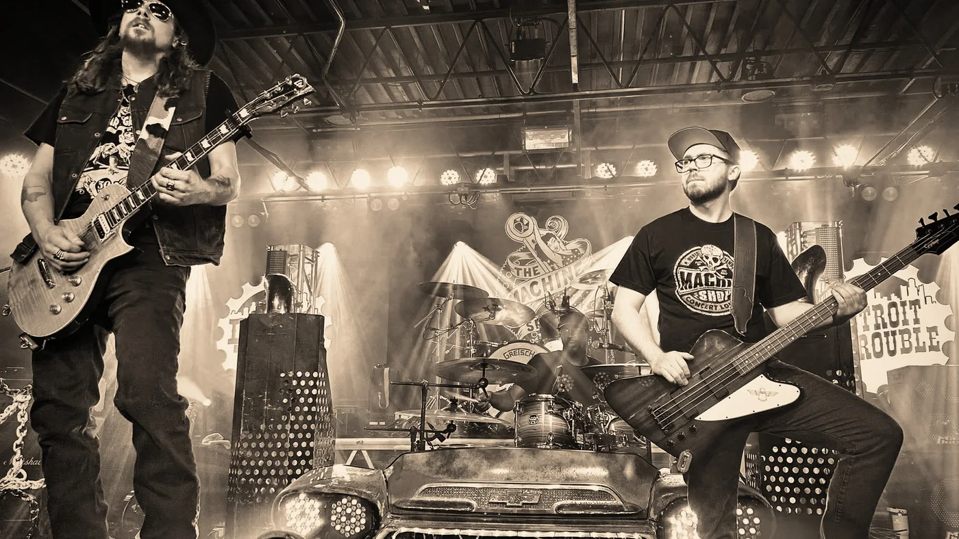 Detroit Trouble live on stage: Kidd Lightning on guitar and Alex Blackburn on bass, with the drum kit behind the band’s Chevy front end.