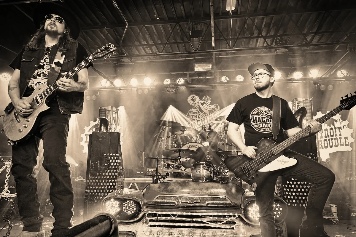Detroit Trouble live on stage: Kidd Lightning on guitar and Alex Blackburn on bass, with the drum kit behind the band’s Chevy front end.