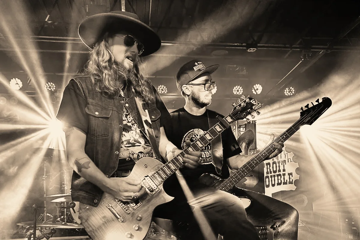 Kidd Lightning and Alex Blackburn playing side by side on stage under stage lights.