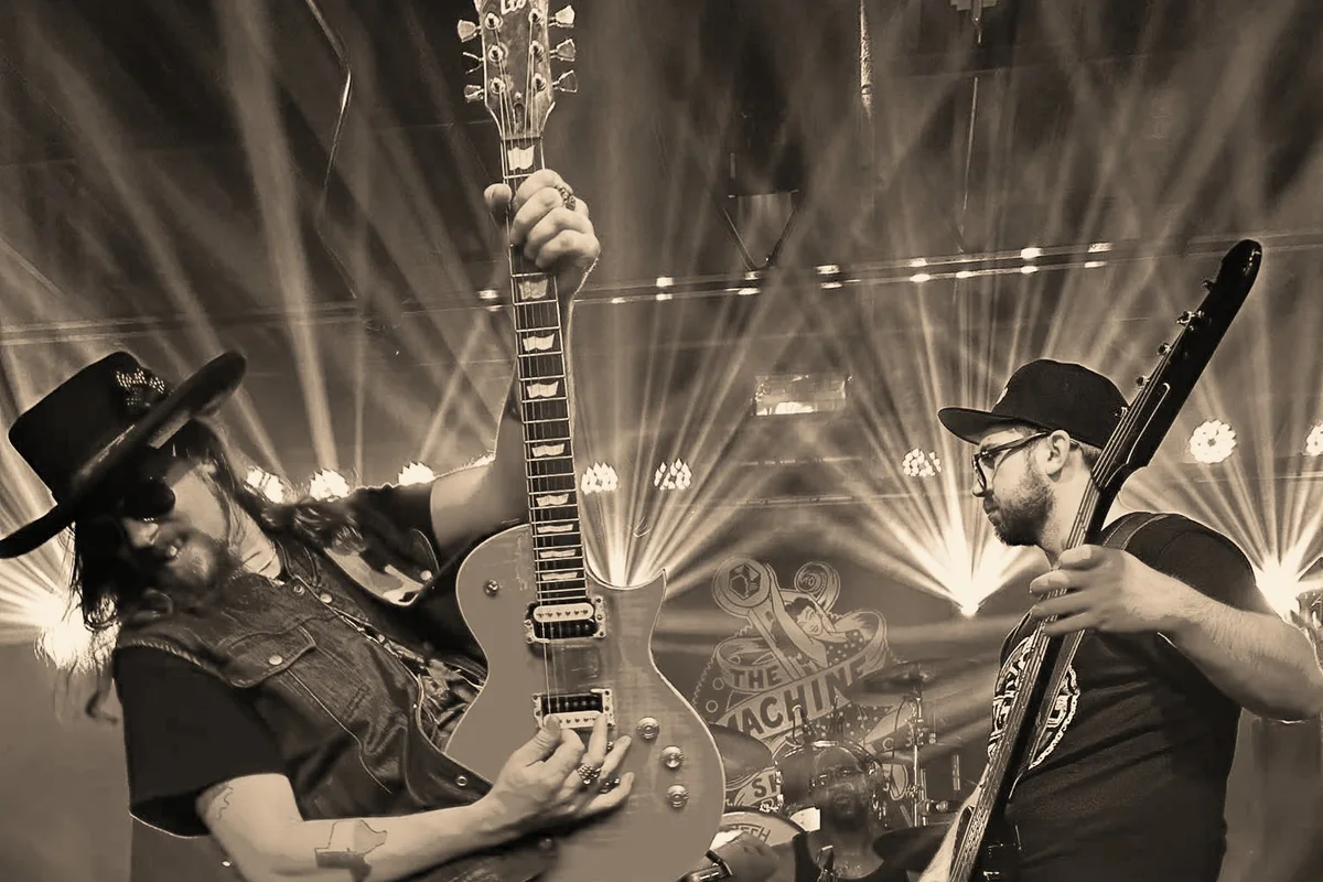 Kidd Lightning holding his guitar upright on stage, with Alex Blackburn on bass beside him.